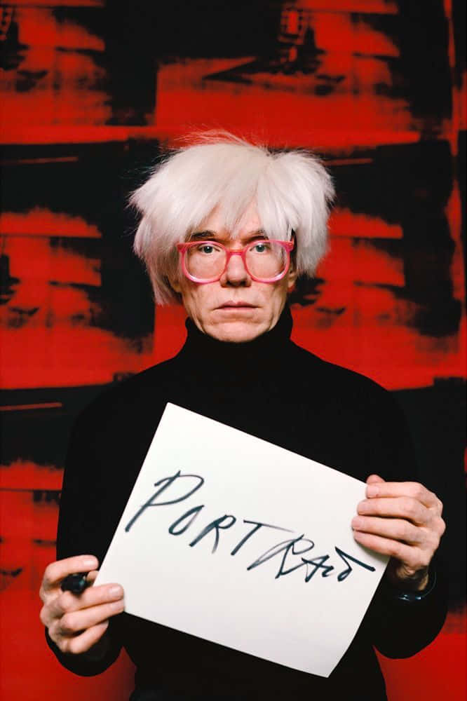 andy warhol 桌布 壁紙 — Andy Warhol 白髮粉紅眼鏡，手持寫有「PORTRAIT」的標語牌，背景為大膽的紅黑抽象圖案。