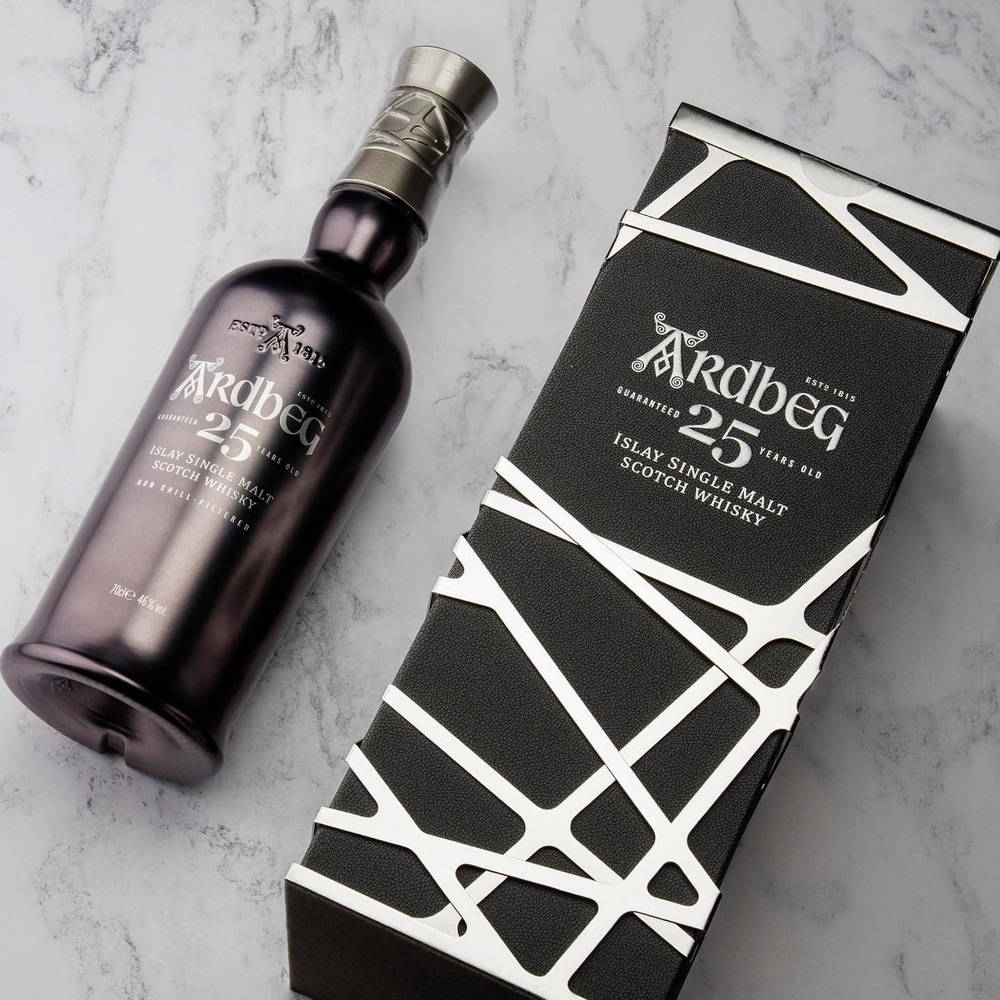 drinks 桌布 壁紙 — Ardbeg 25 Year Old 威士忌的時尚深色酒瓶和幾何圖案盒子放在白色大理石表面上。