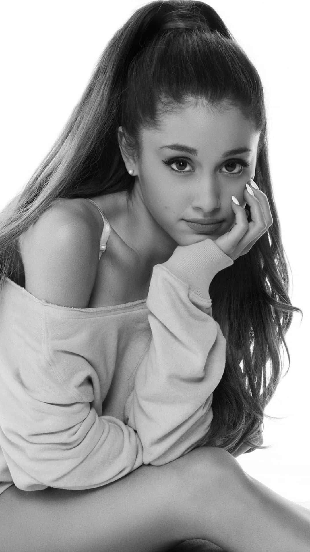  壁紙 — Ariana Grande 以黑白風格擺姿勢，手放在下巴下，長髮紮成高馬尾，直視鏡頭。