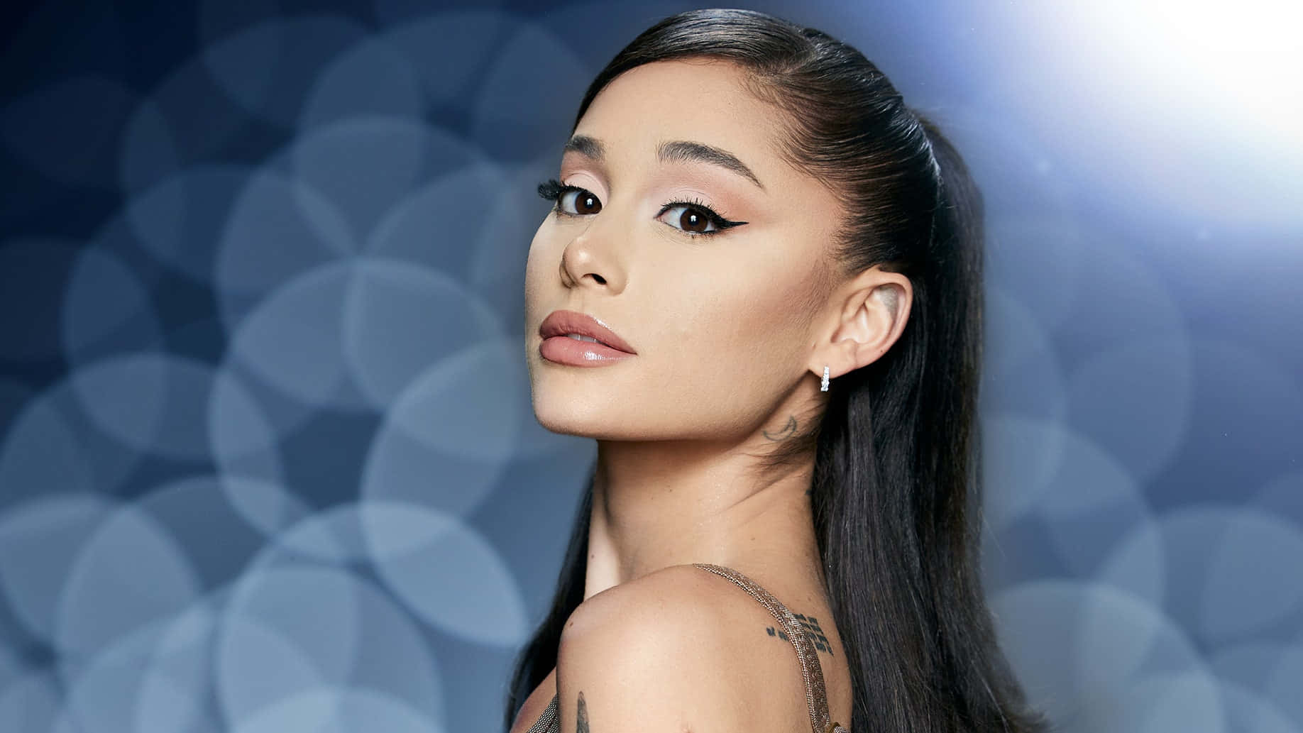 美女 桌布 壁紙 — Ariana Grande 以大膽眼線在柔和藍色散景背景前自信地凝視。