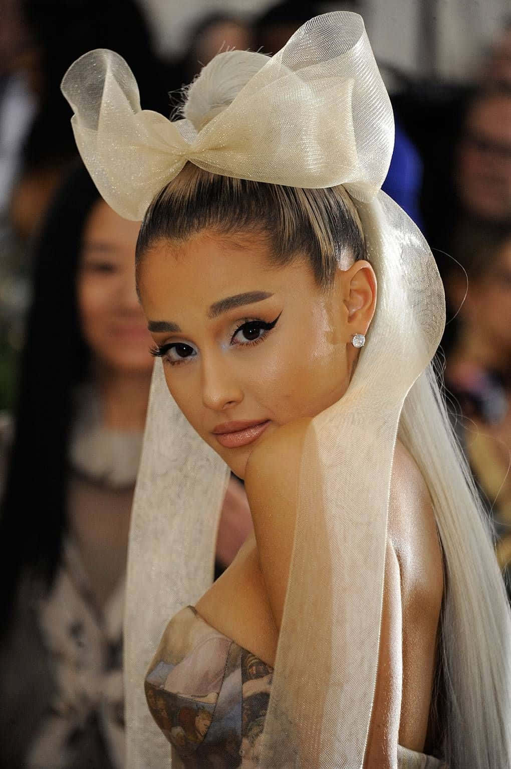 Ariana Grande 在時尚活動中戴著一個大奶油色蝴蝶結和面紗。 — 亞莉安娜·格蘭德 GIF 壁紙