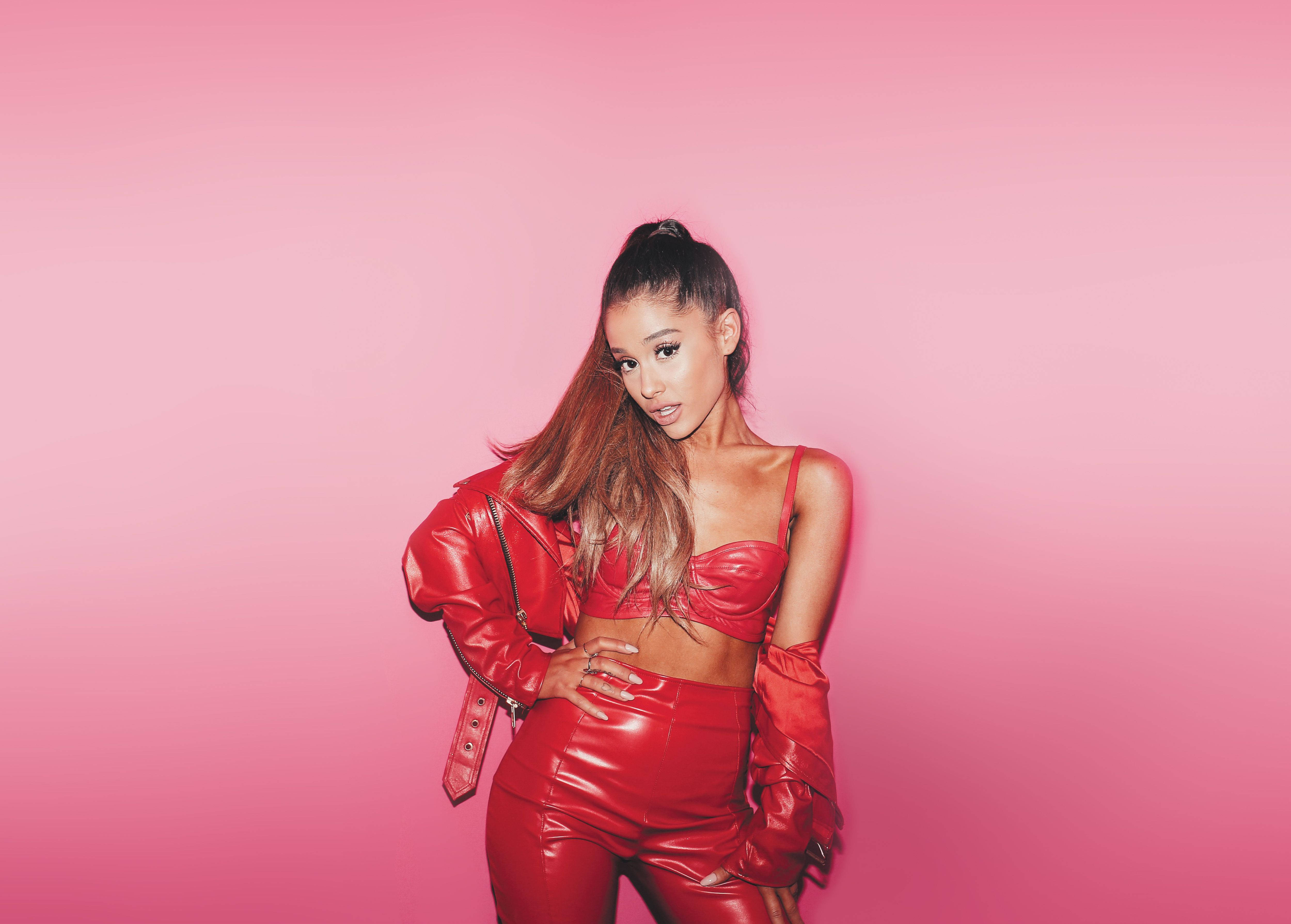 Grande 桌布 壁紙 — Ariana Grande 在純粉色工作室背景前，自信地穿著閃亮的紅色皮革套裝擺姿勢。