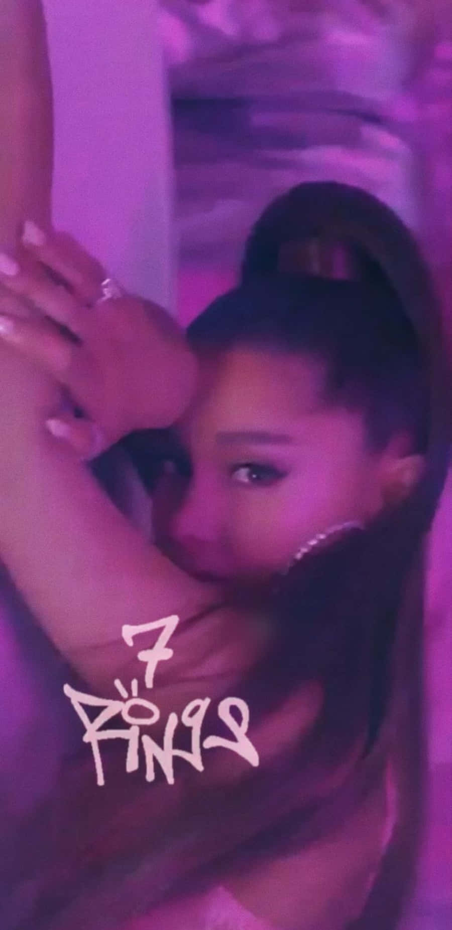 Ariana Grande 7 Rings 桌布 壁紙 — Ariana Grande 在紫色舞台燈光下舉起雙臂擺姿勢，帶有 '7 Rings' 文字疊加。