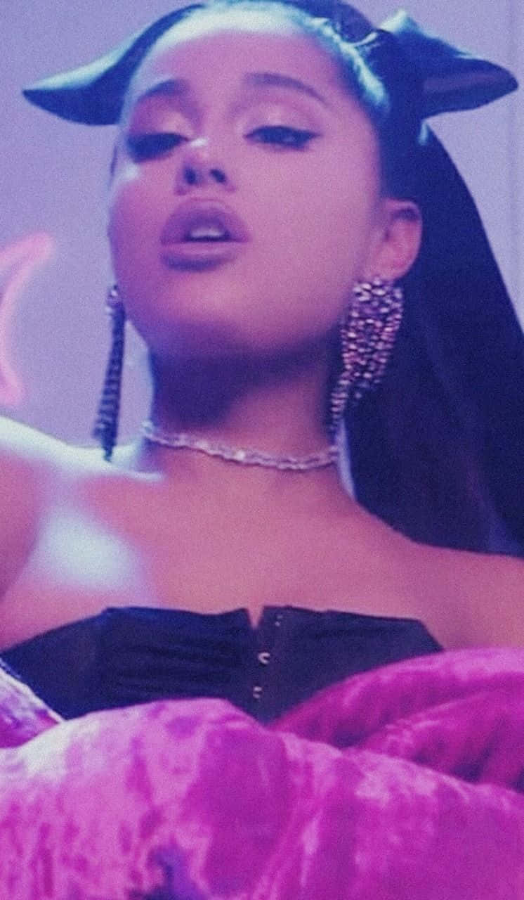 Ariana Grande Aesthetic 桌布 壁紙 — Ariana Grande 戴著貓耳和閃閃發光的珠寶，在紫色燈光背景下擺姿勢。