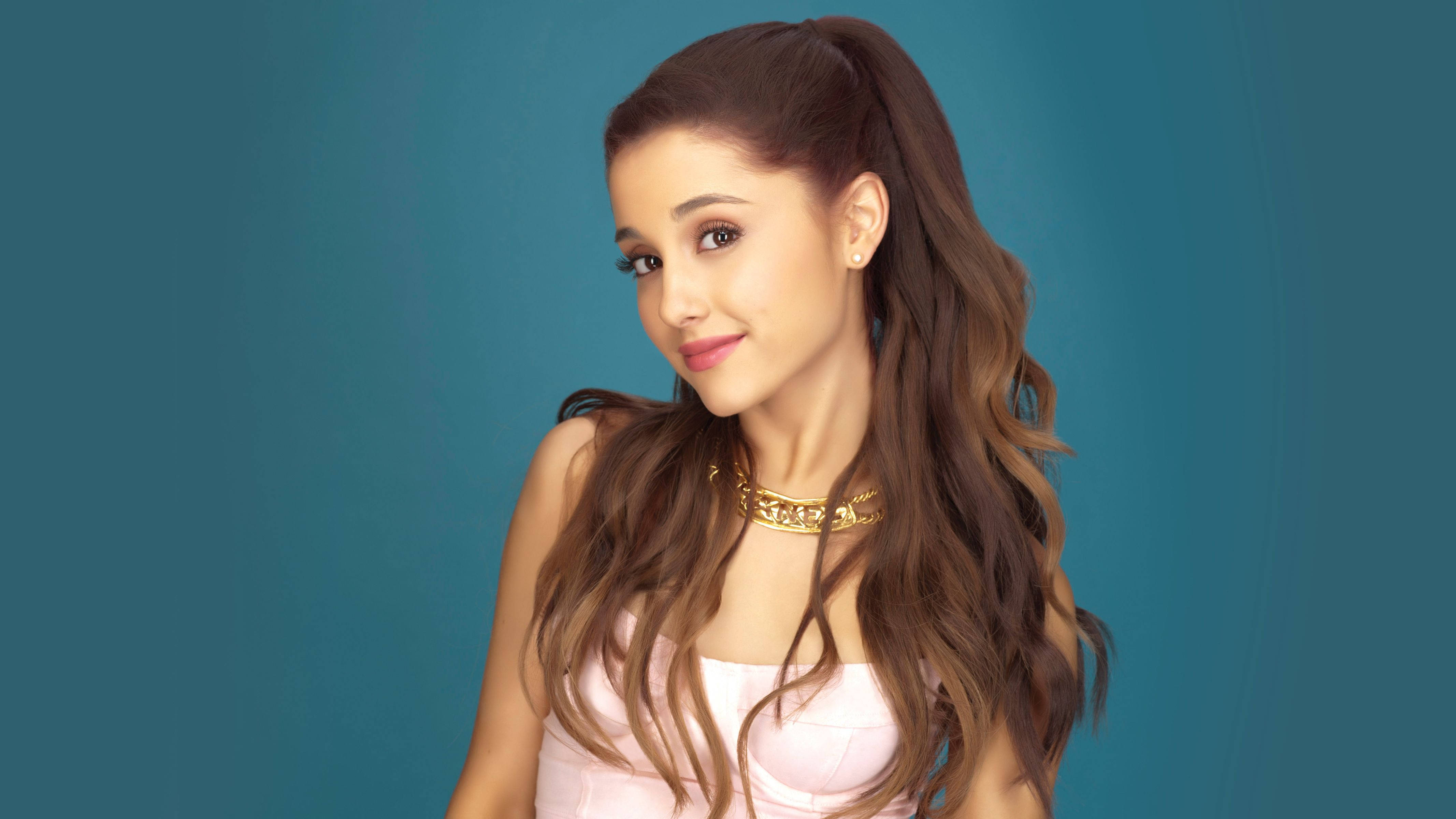 Grande 桌布 壁紙 — Ariana Grande 溫柔微笑，長長的波浪棕色頭髮紮成高馬尾，背景為純青色。