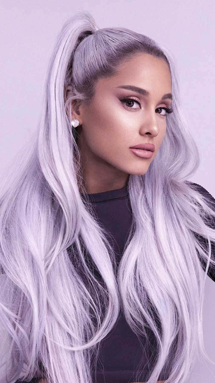 亞莉安娜·格蘭德 桌布 壁紙 — Ariana Grande 留著長長的銀紫色頭髮，梳成高馬尾，背景是柔和的紫色。
