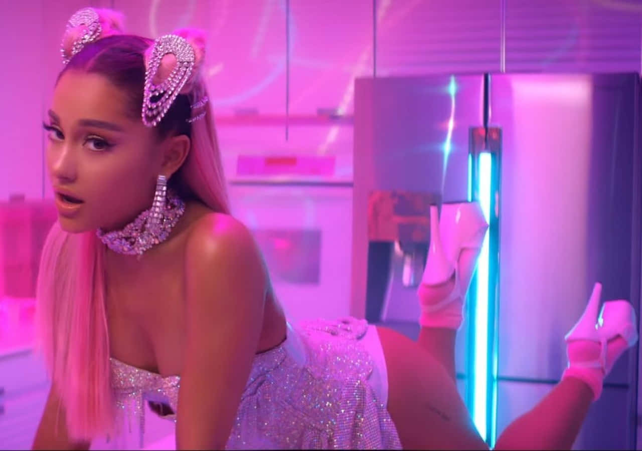 Ariana Grande 7 Rings 桌布 壁紙 — Ariana Grande 身穿閃亮粉紅服裝，戴著鑽石貓耳，靠著未來廚房中的霓虹燈冰箱。