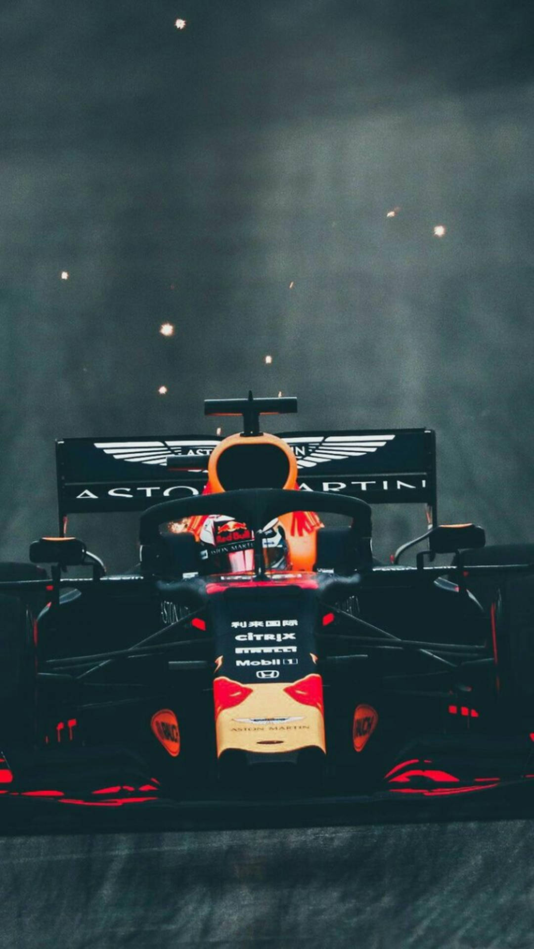 Aston Martin F1賽車，帶有紅色點綴和贊助商標誌，在煙霧和火花下於夜晚。 — F1 iPhone 壁紙 壁紙