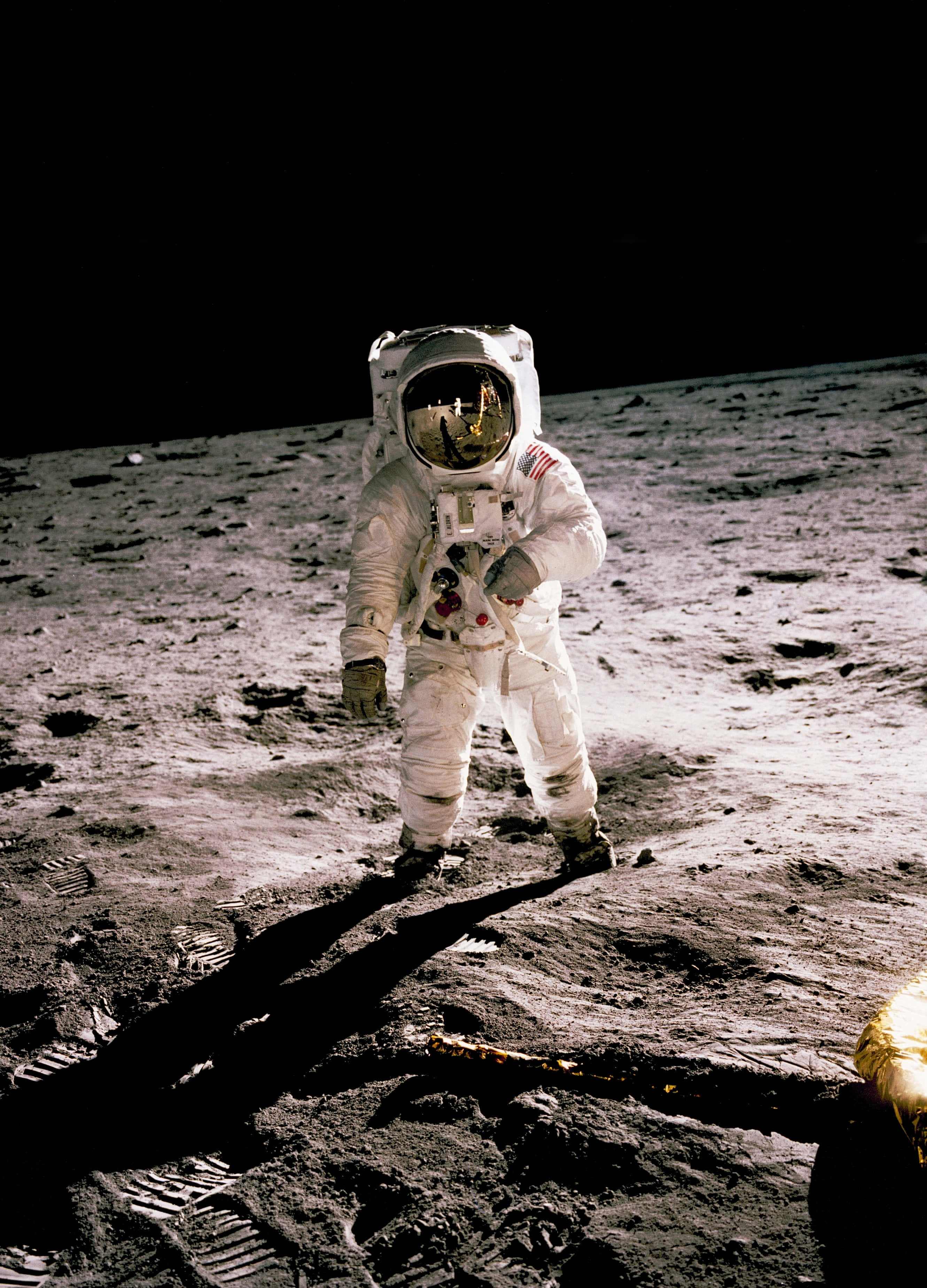 Neil Armstrong 桌布 壁紙 — 一名穿著白色太空衣的太空人站在月球灰色的表面上，在強烈的陽光下投下長長的影子。