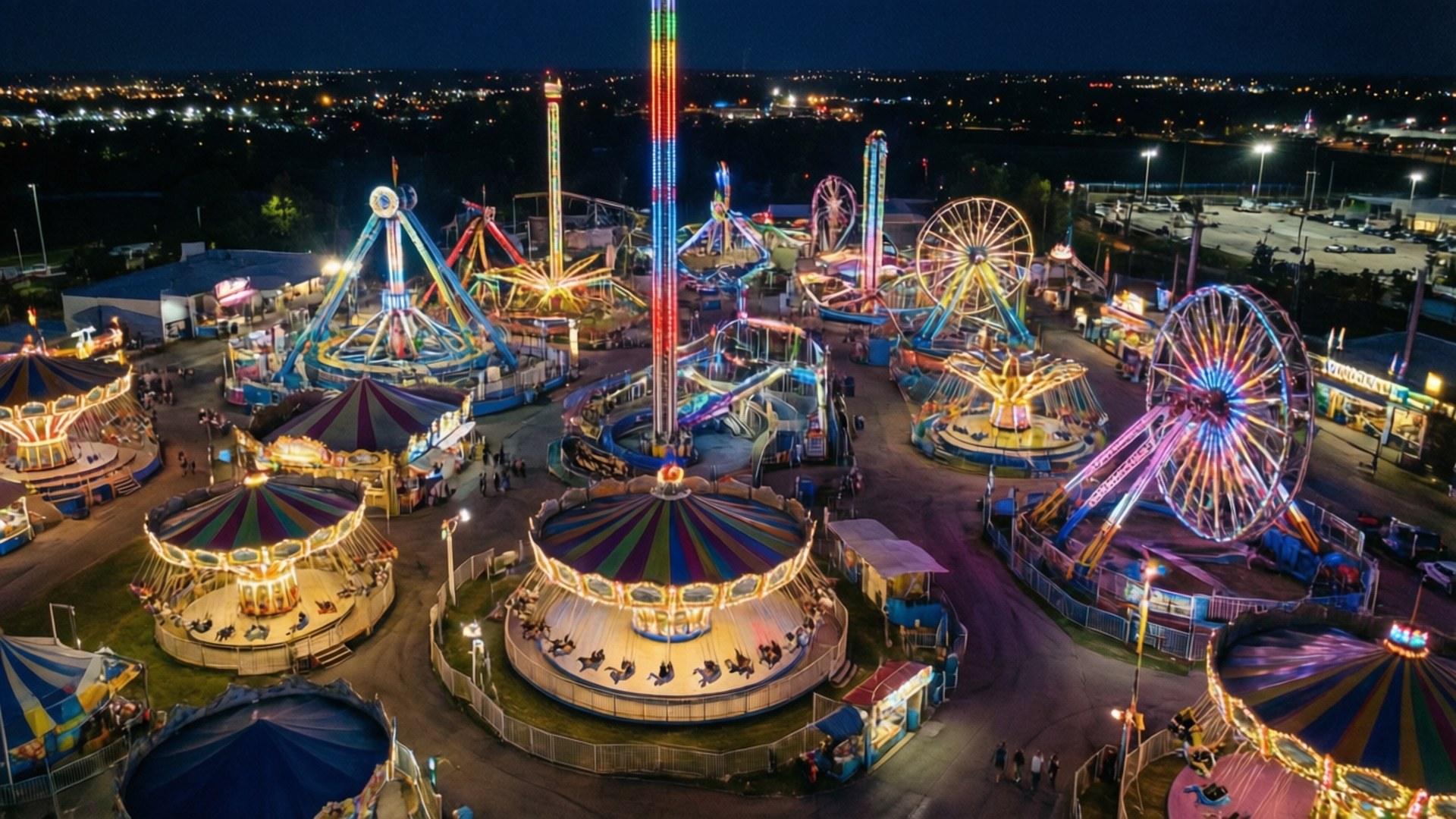 俯瞰Astroworld 壁紙 — 夜間從高空俯瞰充滿活力的遊樂園，發光的遊樂設施和五彩繽紛的燈光點亮了黑暗的天空。