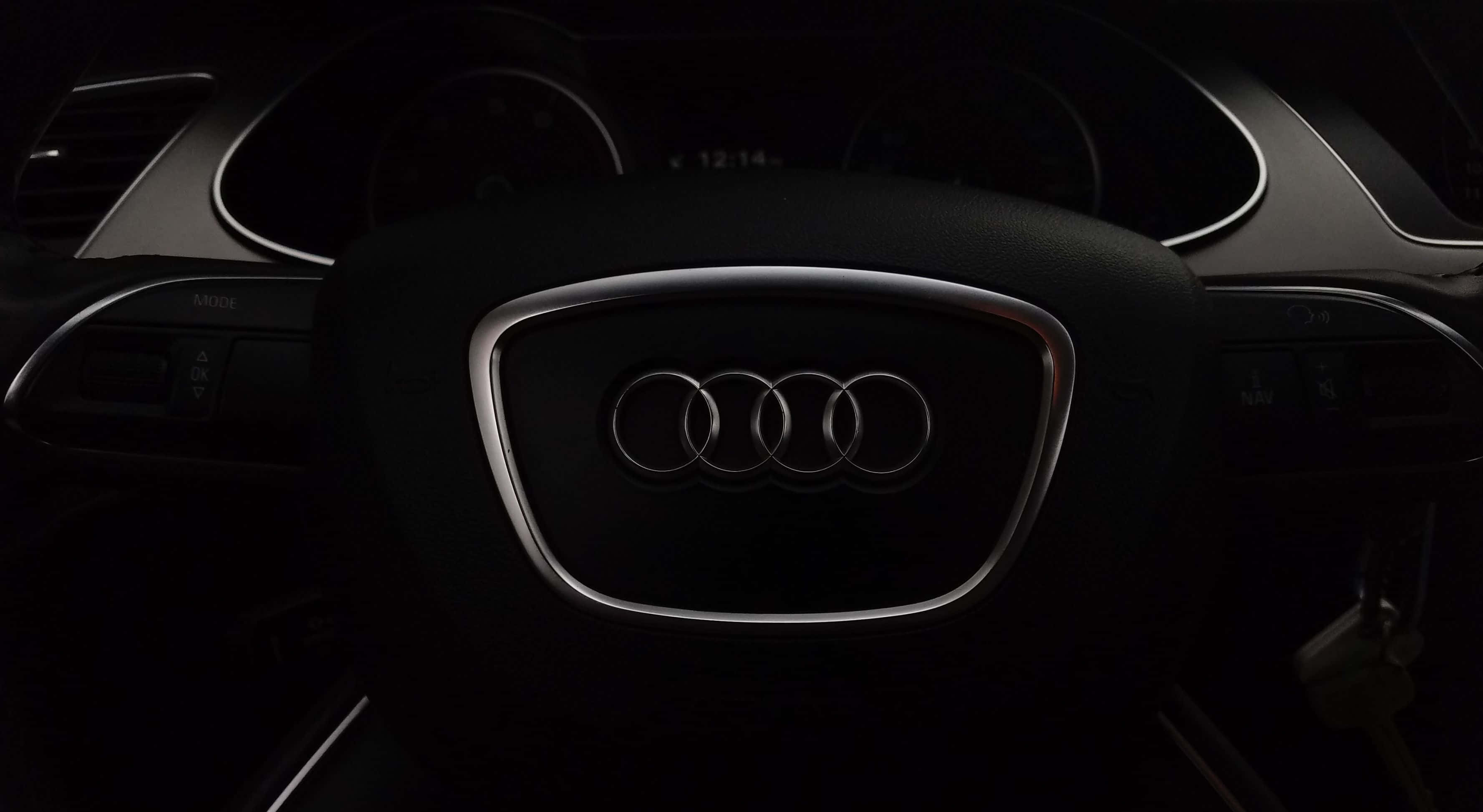 Audi A4 桌布 壁紙 — Audi 標誌置中於方向盤上，車廂內光線昏暗，並有發光的數位時鐘。