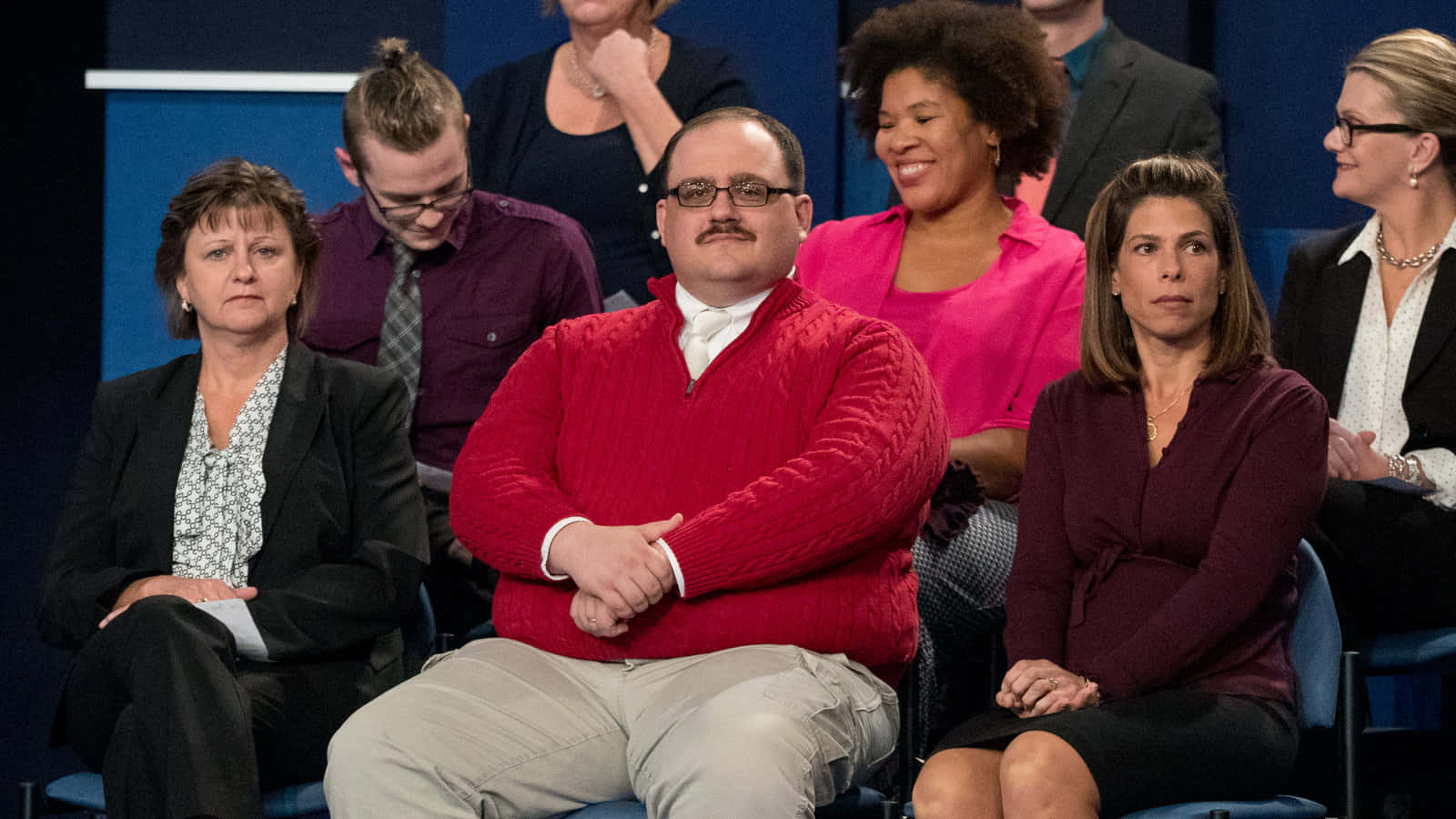 Red Sweater 桌布 壁紙 — 在攝影棚內的觀眾，表情多樣，衣著色彩繽紛。