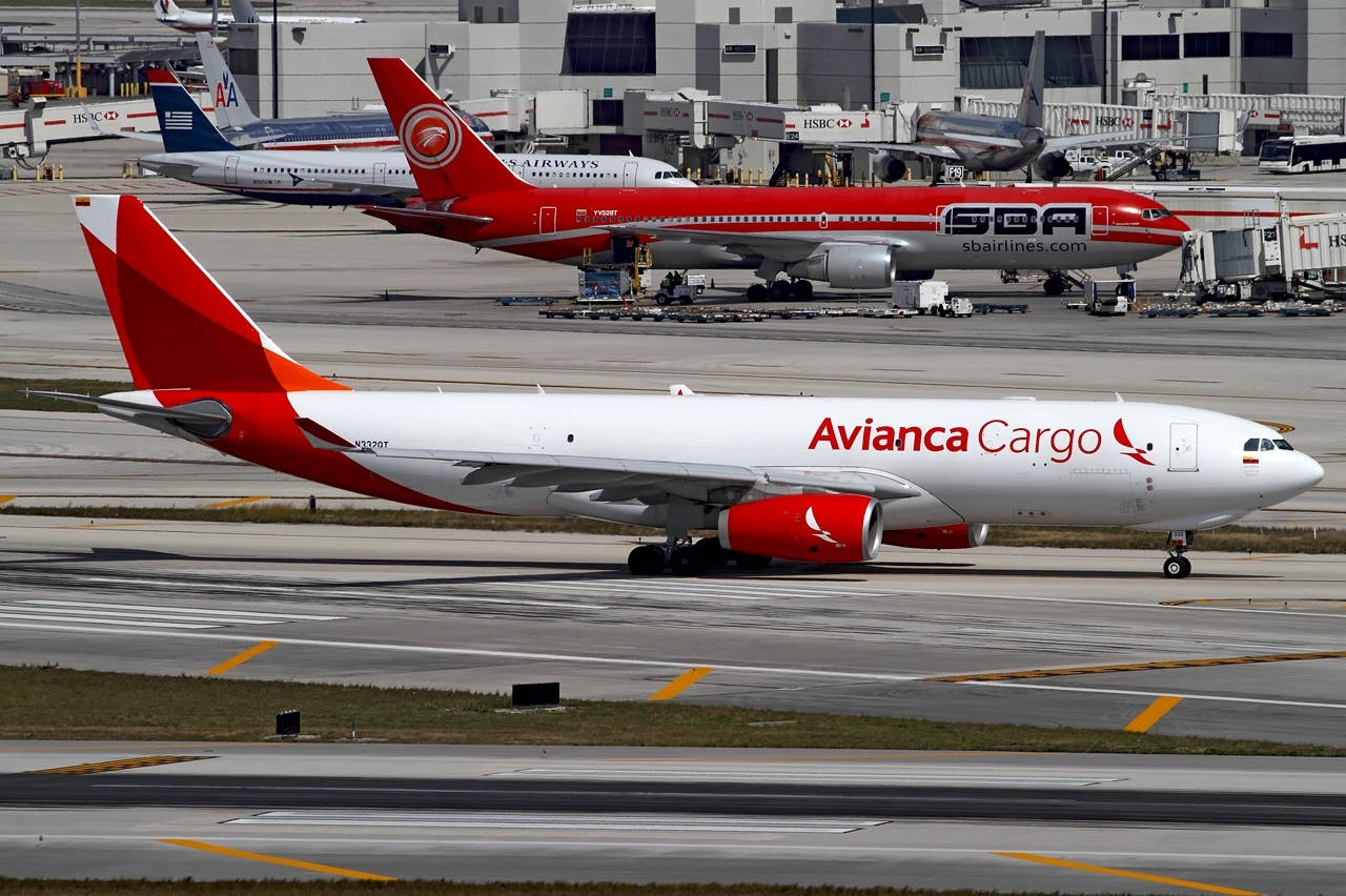 Plane 桌布 壁紙 — Avianca Cargo 飛機在機場停機坪上滑行，紅白塗裝，背景有其他飛機等候。