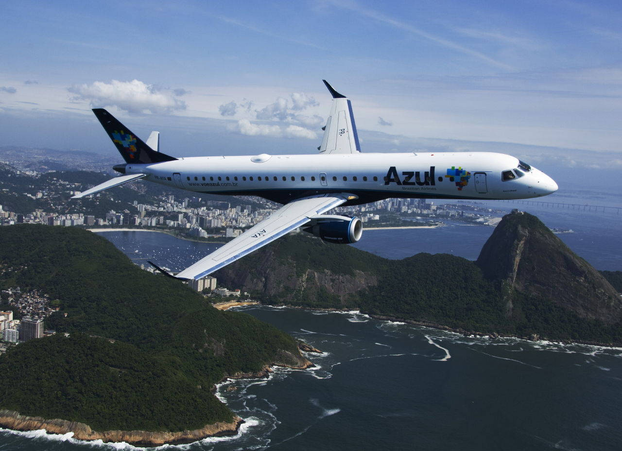 Island 桌布 壁紙 — Azul Airlines 噴射機在里約熱內盧標誌性海岸線、糖麵包山和下方城市景觀上空翱翔，天空湛藍。