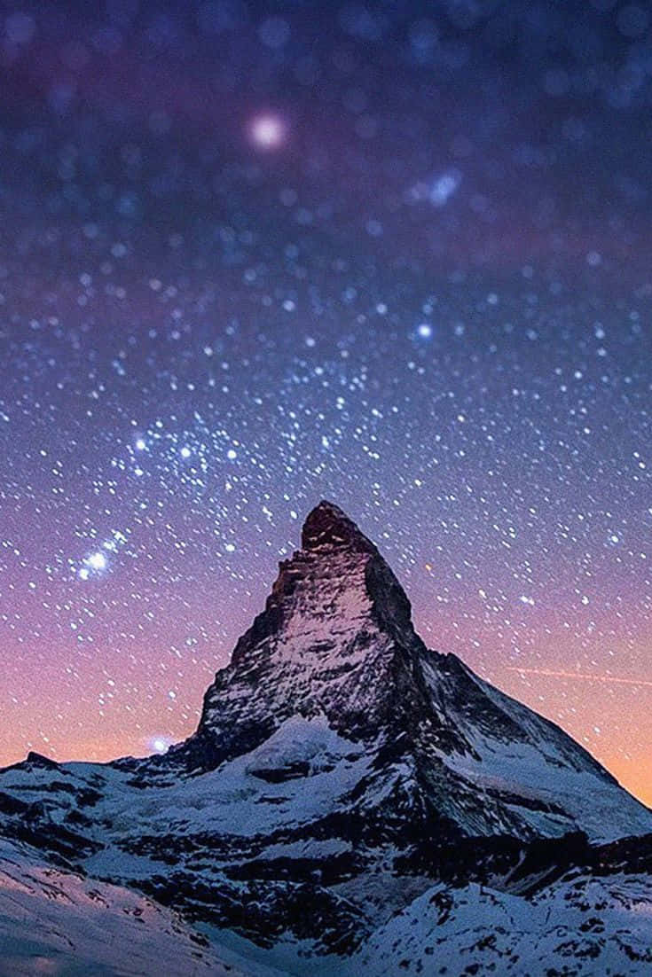  壁紙 — 白雪覆蓋的馬特洪峰在充滿紫色和粉紅色色調的 vibrant 星空暮色天空下聳立。