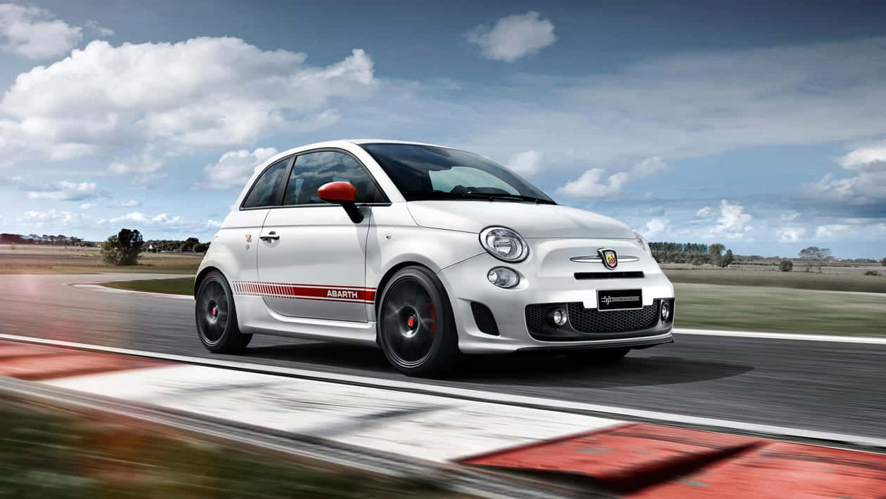 Fiat 500 桌布 壁紙 — 一輛白色 Abarth 500 跑車在部分多雲的天空下，在賽道上高速行駛，瀝青路面呈現動態模糊效果。