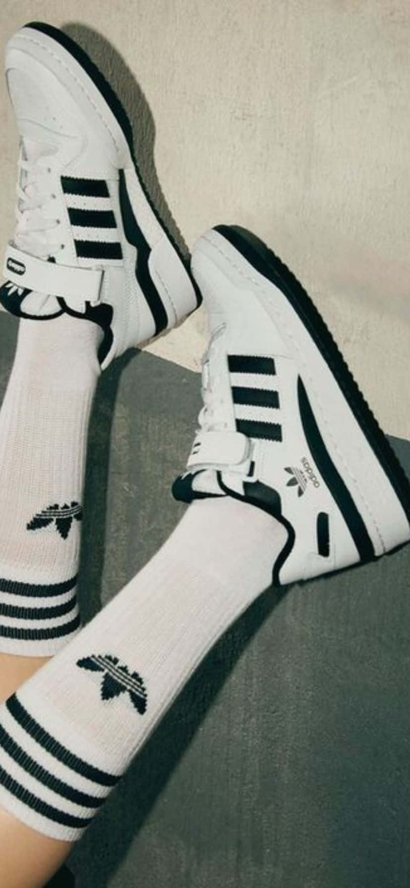  壁紙 — 白色adidas運動鞋搭配黑色條紋，配上相襯的襪子，放置在帶有紋理的灰色表面上。
