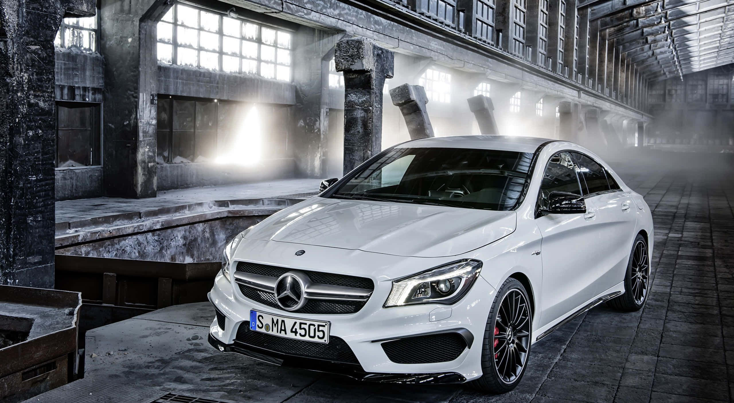 Mercedes Benz Cla-class 桌布 壁紙 — 一架流線型白色賓士CLA 45 AMG跑車在霧氣籠罩的廢棄工廠內，於戲劇性的工業燈光下閃閃發光。