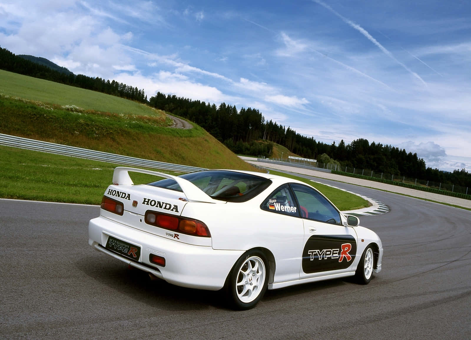 Honda Integra 桌布 壁紙 — 一輛白色本田Type R跑車在晴朗藍天和零星白雲下，沿著蜿蜒的賽道奔馳。