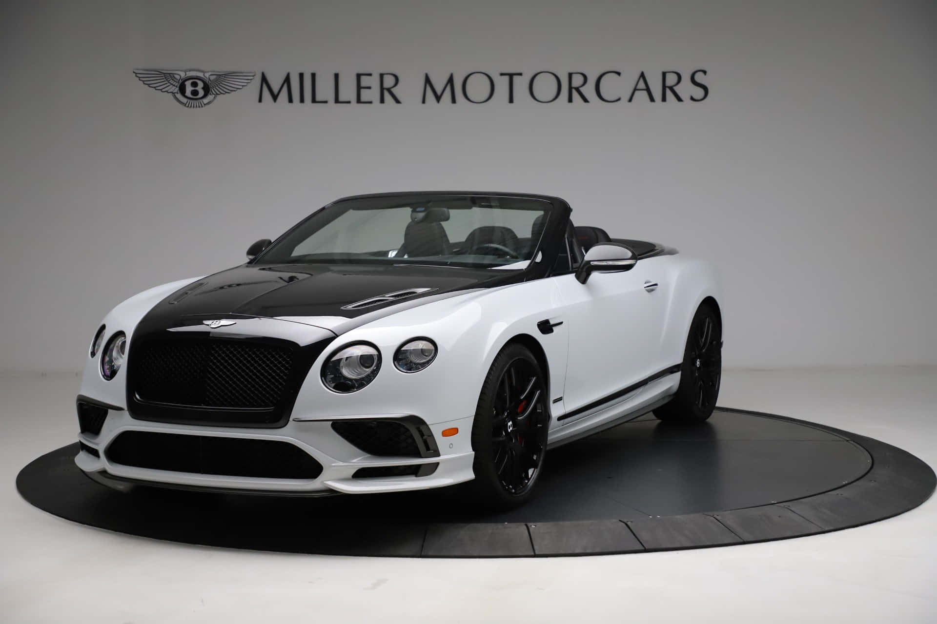 Bentley Continental Supersports 桌布 壁紙 — 一輛純白色的賓利 Continental GT 敞篷車，帶有黑色飾邊和輪圈，在工作室燈光下展示於圓形平台上。