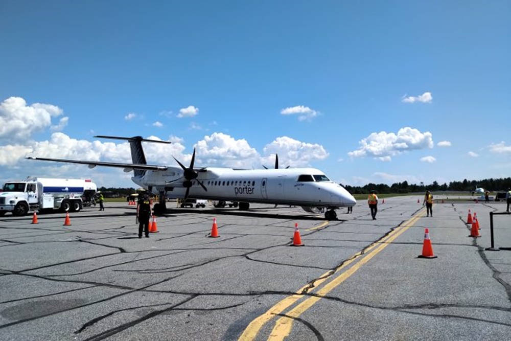 白色波特飛機在停機坪上，有地勤人員和橙色錐體，藍天白雲 — Air Jordan 壁紙