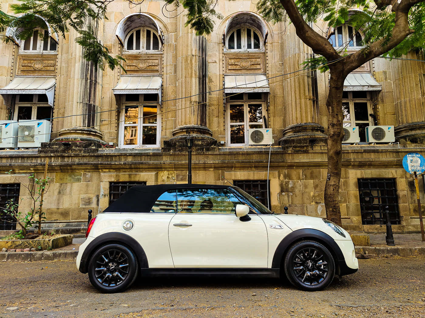 Mini Cooper S Convertible 桌布 壁紙 — 一輛白色敞篷迷你庫柏停在一棟歷史悠久的石造建築前，建築有拱形窗戶，樹枝在頭頂上。