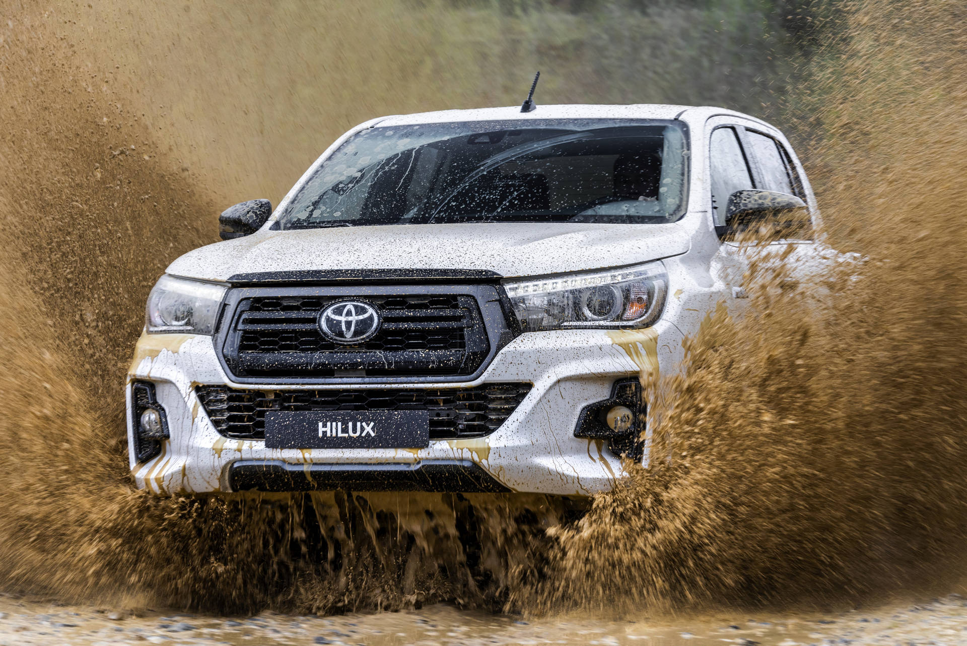 白色豐田 Hilux 貨車在泥水中行駛，水花四濺。 — Toyota Supra 壁紙