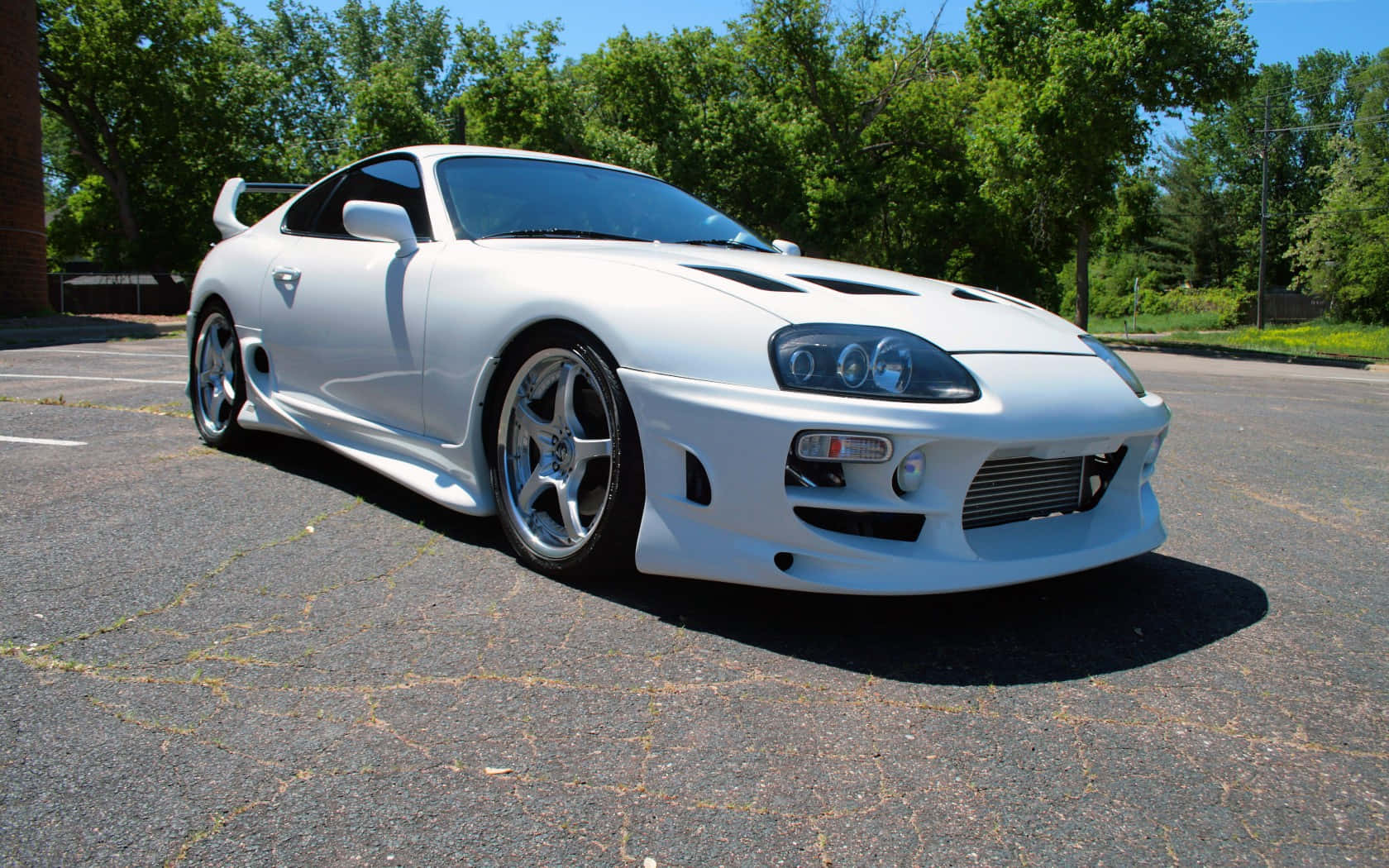 白色豐田Supra跑車停放在裂開的瀝青上，處於強烈陽光下。 — Toyota Supra 壁紙