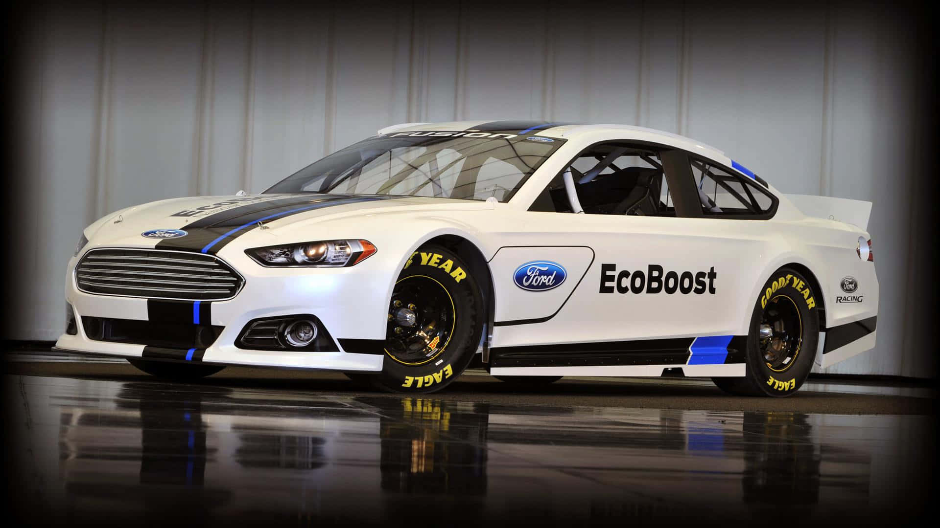 Ford Fusion 桌布 壁紙 — 一輛白色福特EcoBoost賽車，帶有黑色和藍色點綴，在工作室燈光下展示在光澤地板上。