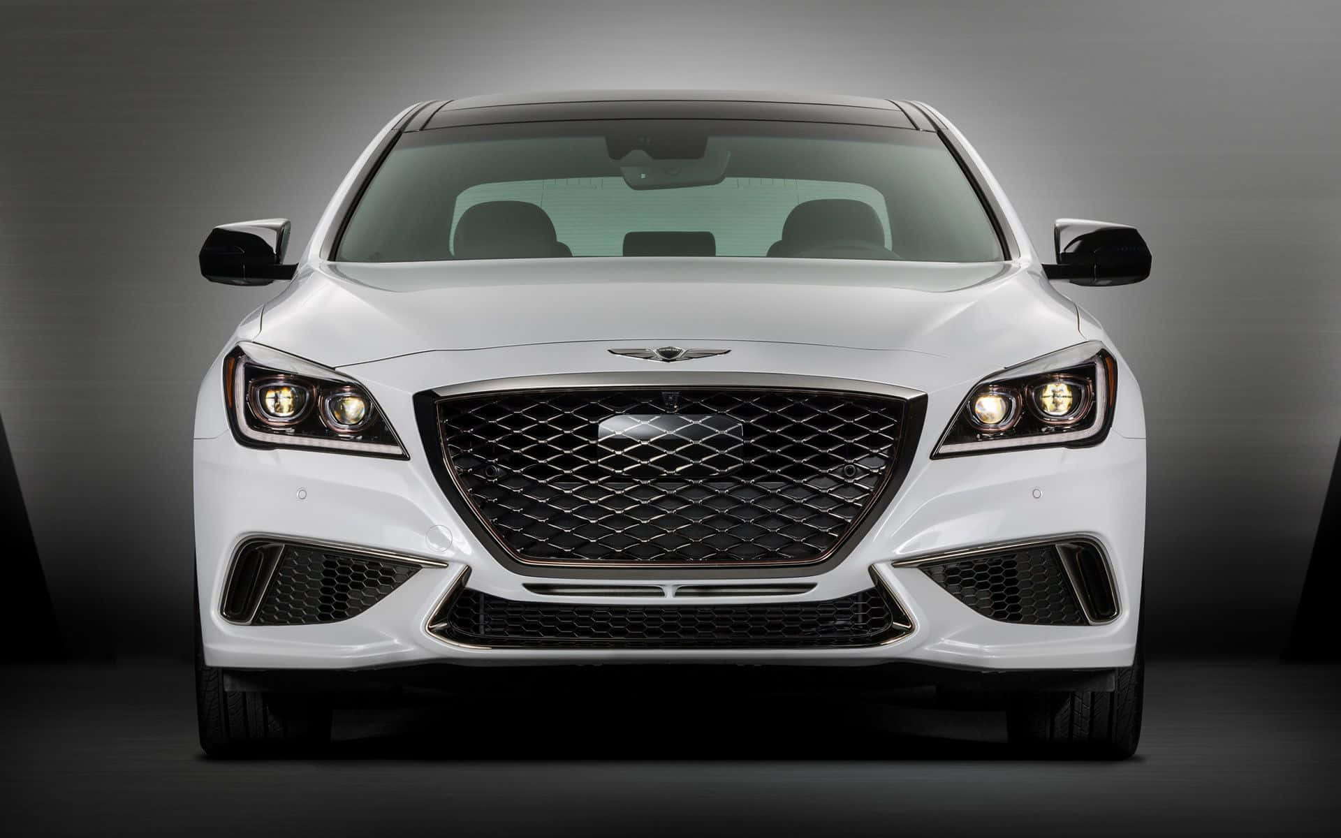 Genesis G80 桌布 壁紙 — 一輛純白色豪華轎車正面朝前，配備發光頭燈和醒目進氣格柵，背景為深色攝影棚。