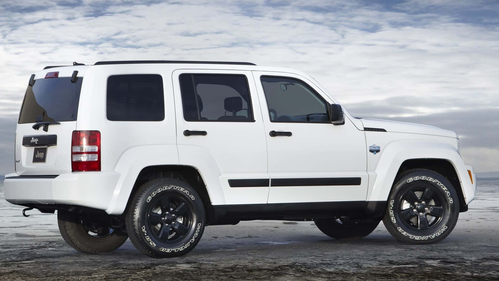 Jeep Liberty 桌布 壁紙 — 一輛白色Jeep Wrangler在陰天之下，停放在冰凍的凍原上，配備黑色輪圈和輪胎。