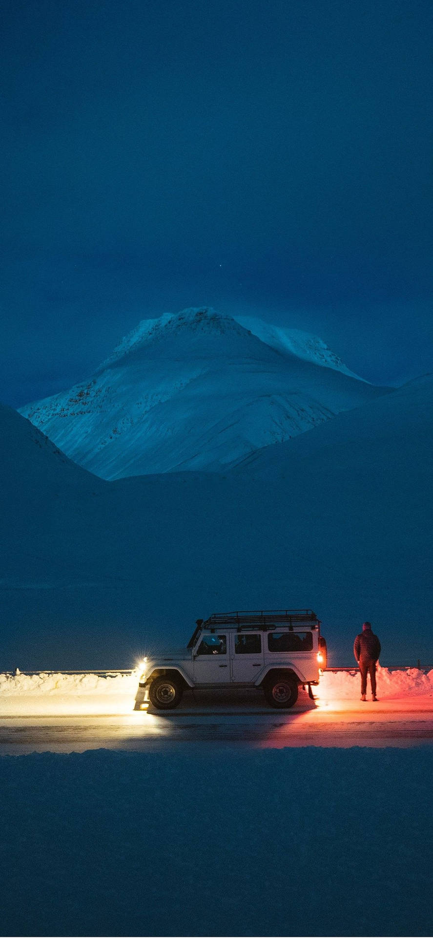 白色吉普車和人在夜間站在雪地中靠近山 — iPhone 11 Pro Max 壁紙