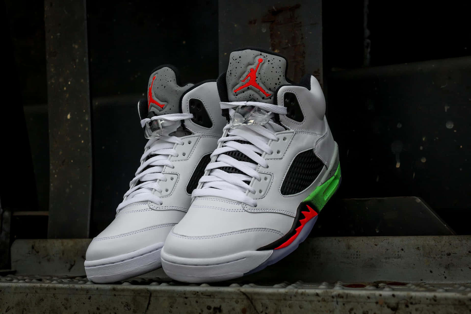白色Jordan 5運動鞋，帶有紅色和綠色點綴，在混凝土邊緣上。 — Jordan球鞋 壁紙