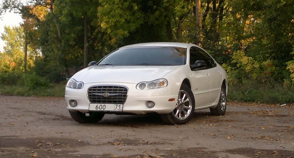 Chrysler Lhs 桌布 壁紙 — 一輛白色克萊斯勒300轎車停在鋪滿落葉的泥土路上，周圍是秋天的樹木。