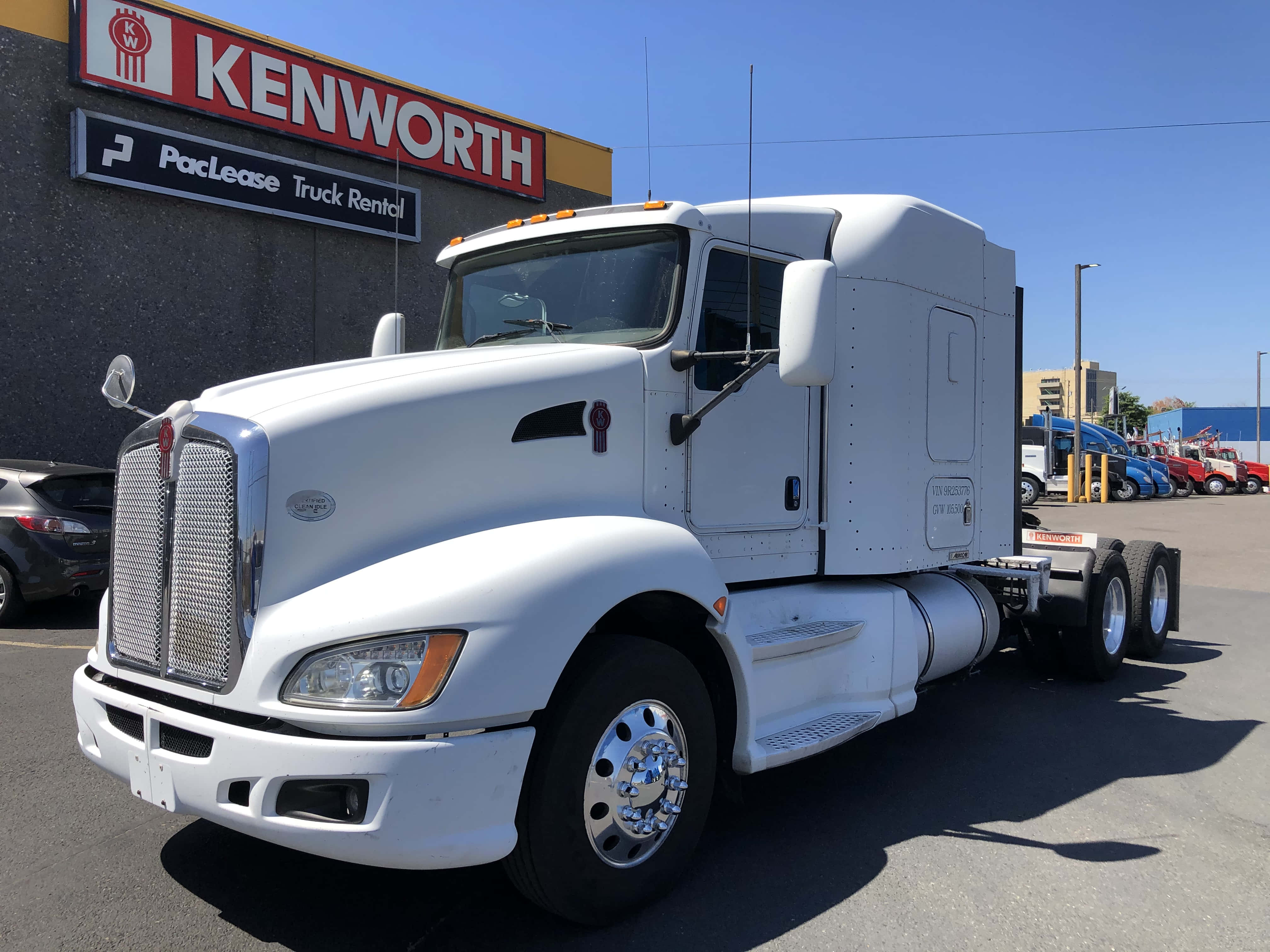 Kenworth T660 桌布 壁紙 — 一輛純白色的Kenworth半掛卡車在明亮的陽光下閃閃發光，停在PacLease租賃設施前。