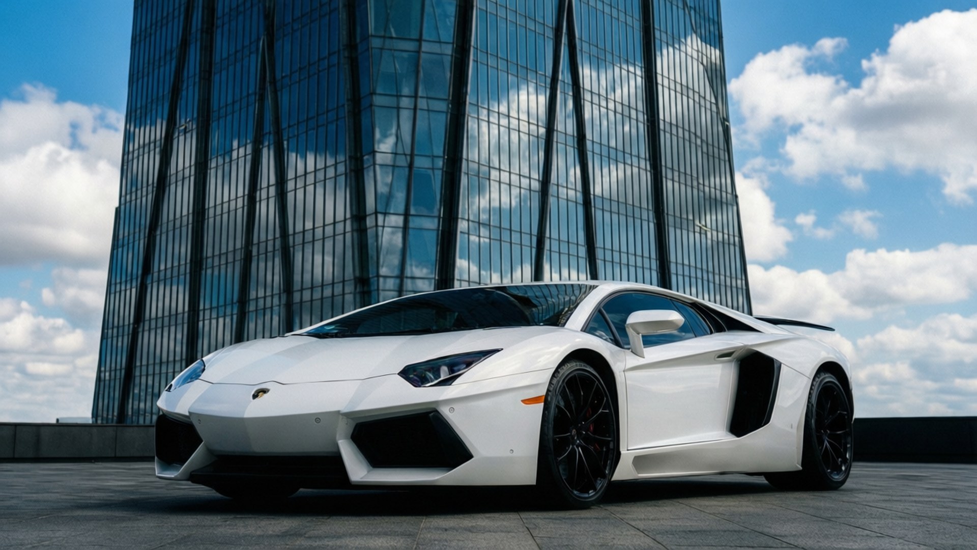White Lamborghini Urban 壁紙 — 一輛純白色藍寶堅尼Aventador停放在屋頂上，背景是現代玻璃摩天大樓，天空湛藍，白雲朵朵。