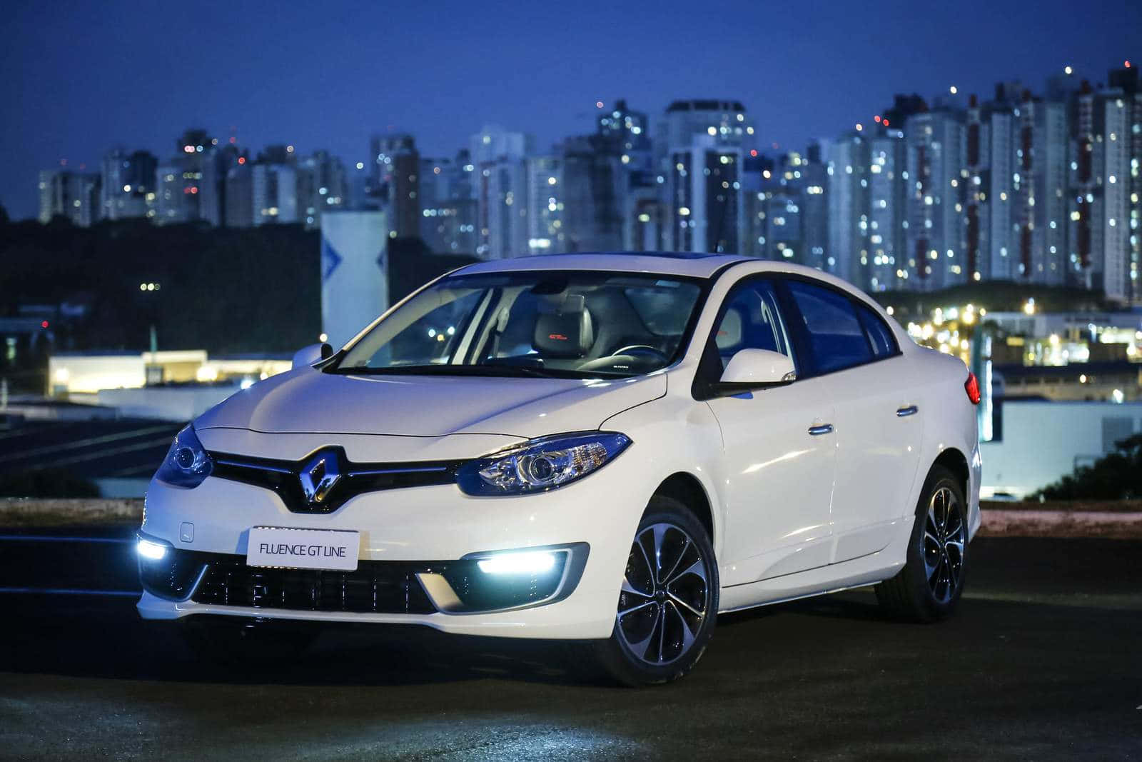 Renault Fluence 桌布 壁紙 — 一輛白色雷諾Fluence GT Line轎車在夜燈下閃耀，背景是燈火通明的城市摩天大樓。