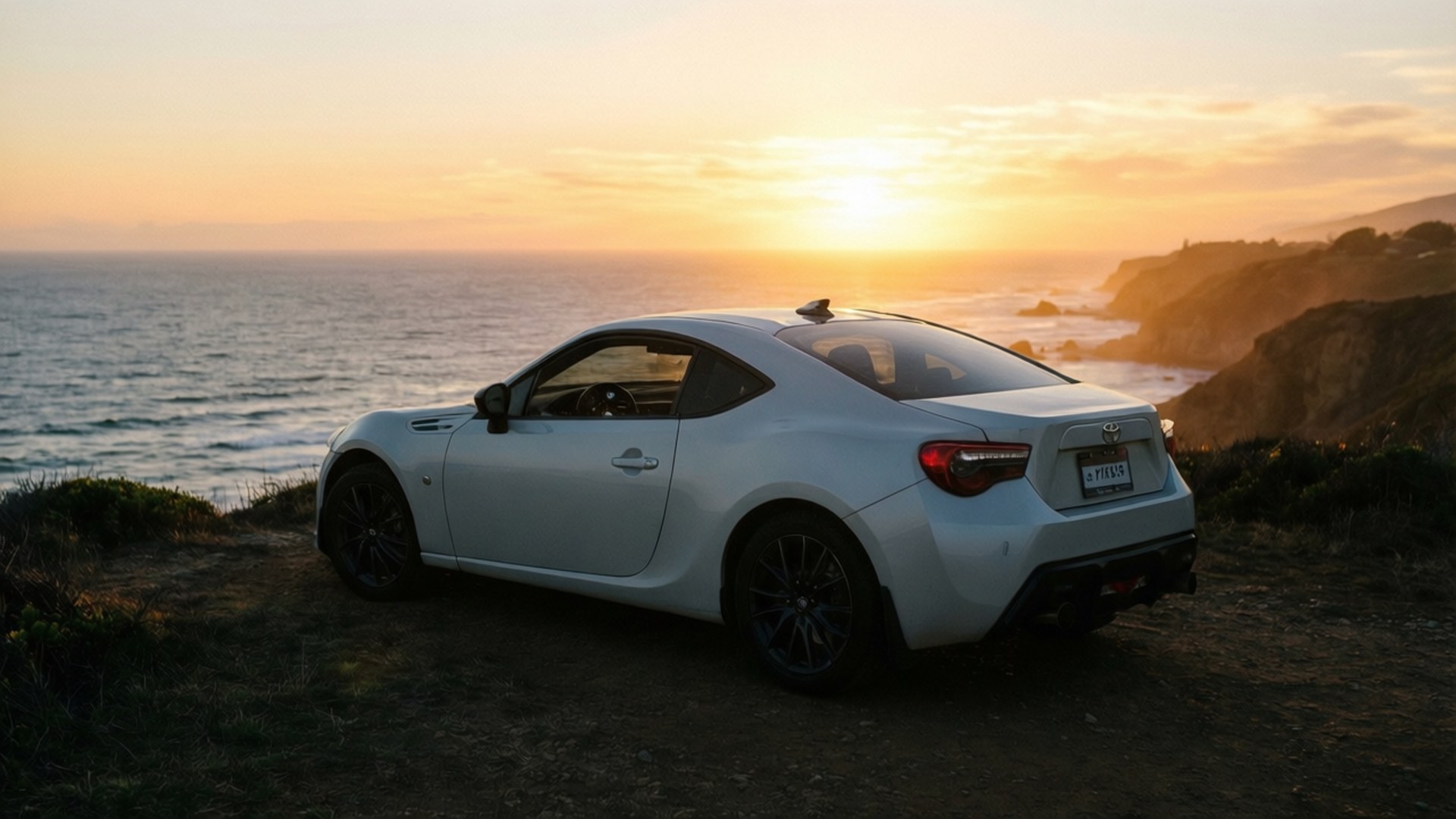 GT86 Sunset Serenity 壁紙 — 一輛白色跑車停泊在懸崖邊，俯瞰金色日落時分的海洋。