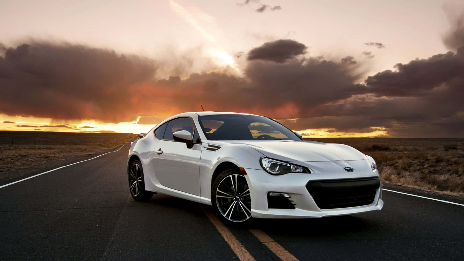 白色跑車在沙漠公路上日落時分行駛。 — Toyota Supra 壁紙