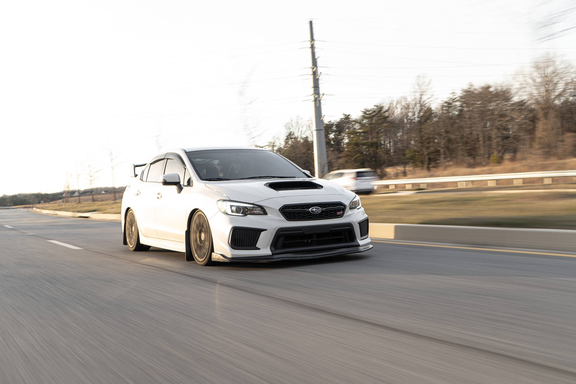 白色Subaru WRX STI在高速公路上行駛，背景模糊。 — 4K 壁紙