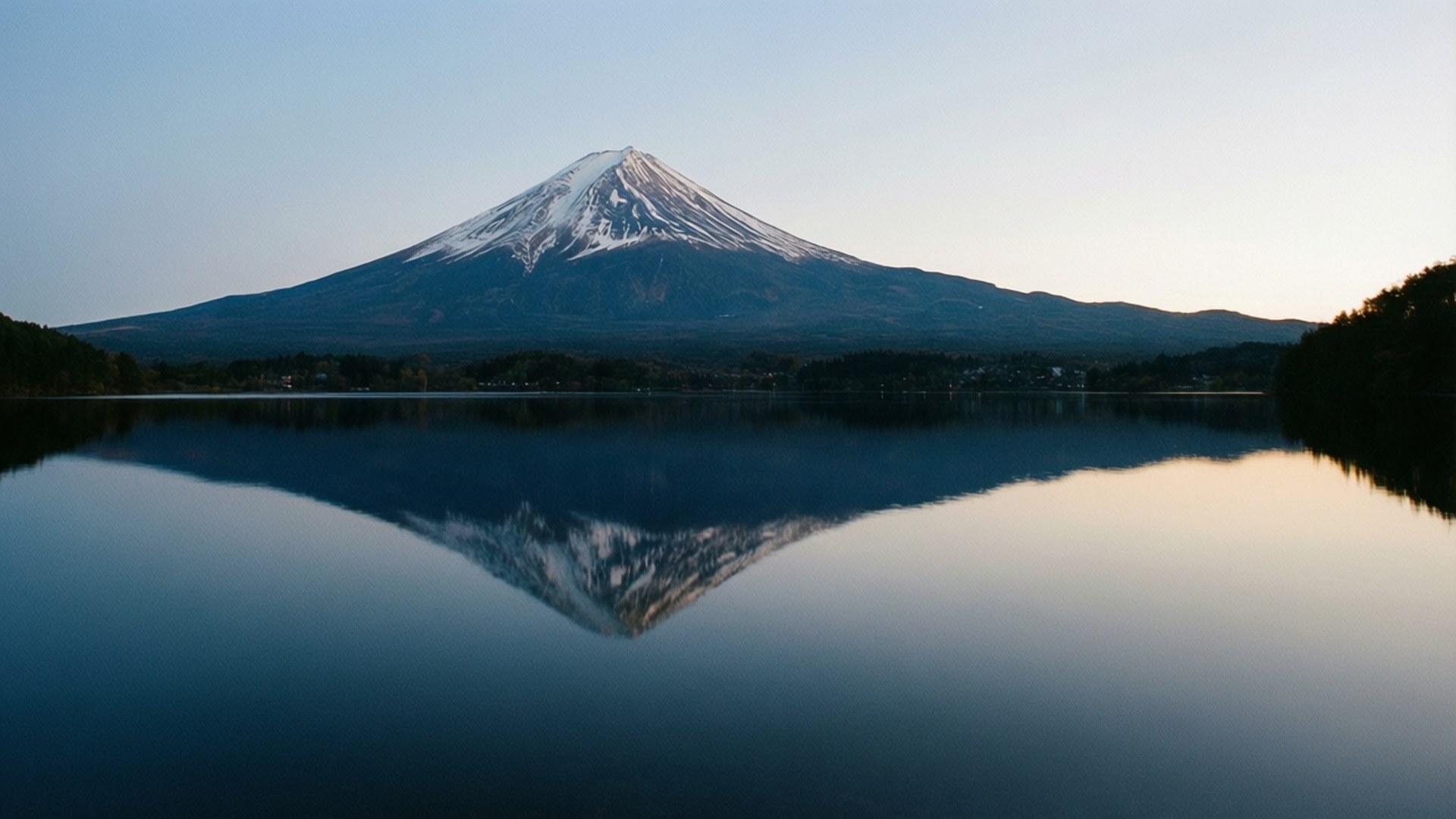 Mountain Lake Reflection 壁紙 — 白雪覆蓋的富士山在黎明時分完美倒映在平靜的湖面上，呈現柔和的藍色和金色色調。