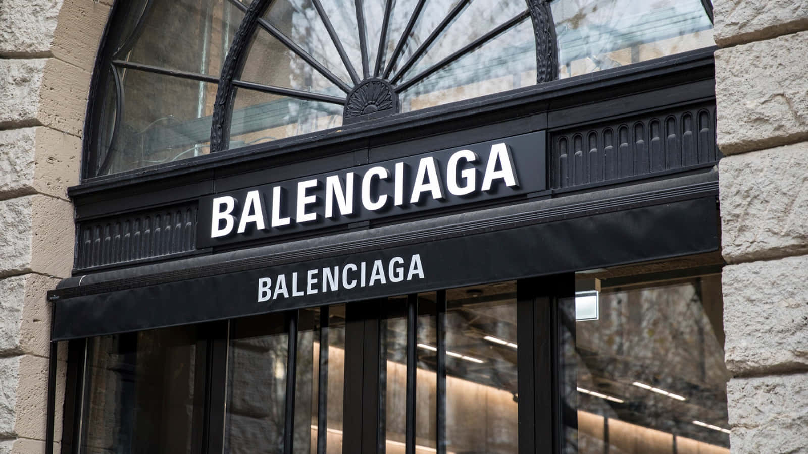 巴黎世家 桌布 壁紙 — Balenciaga 店鋪入口特寫，黑色招牌上帶有粗體白色字體，以石頭和拱形玻璃框住。
