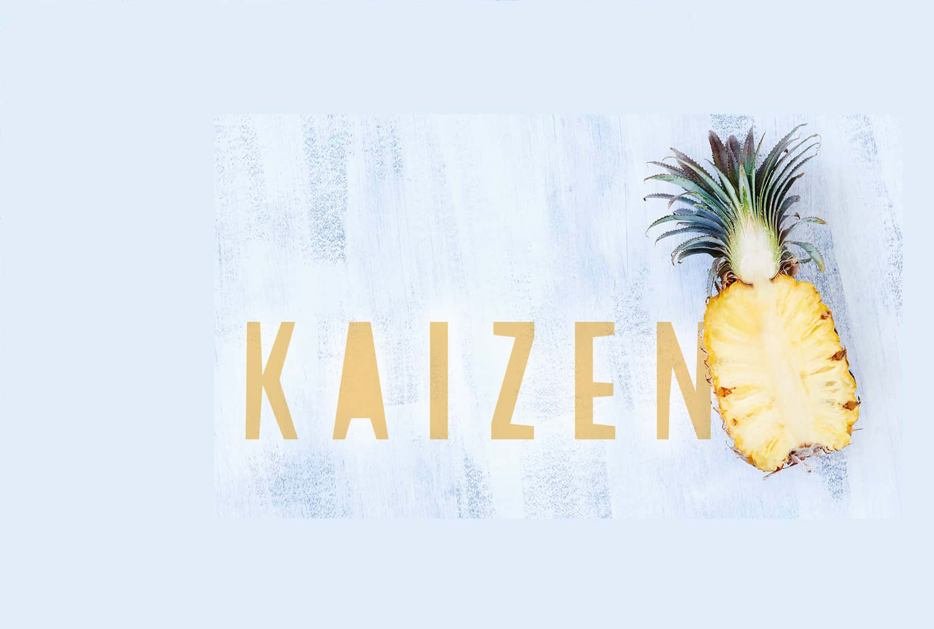  壁紙 — 半個鳳梨放在紋理淺藍色表面上，旁邊是粗體金色 'KAIZEN' 文字。