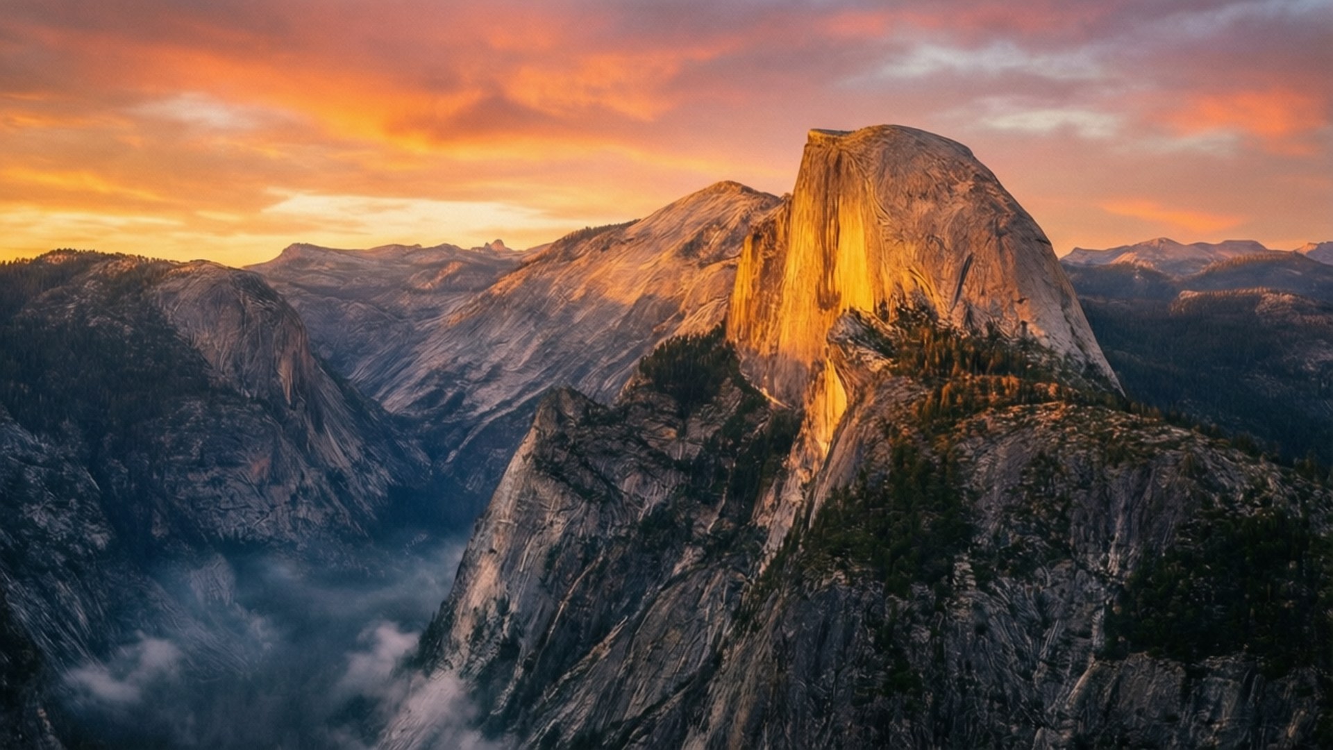Half Dome Golden Sunrise 壁紙 — 半圓頂山沐浴在金色的日落光線中，下方有橙色雲朵和薄霧。