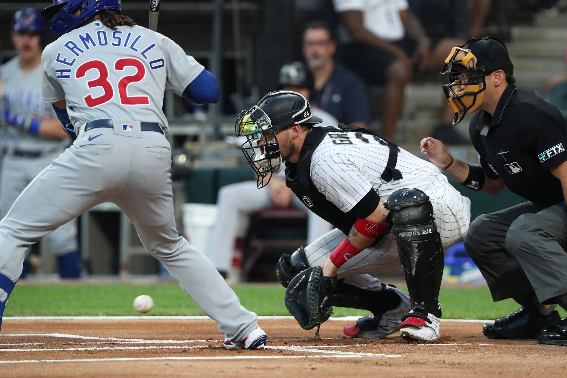 棒球打者揮棒擊球，捕手和裁判蹲在本壘板後方。 — MLB 壁紙