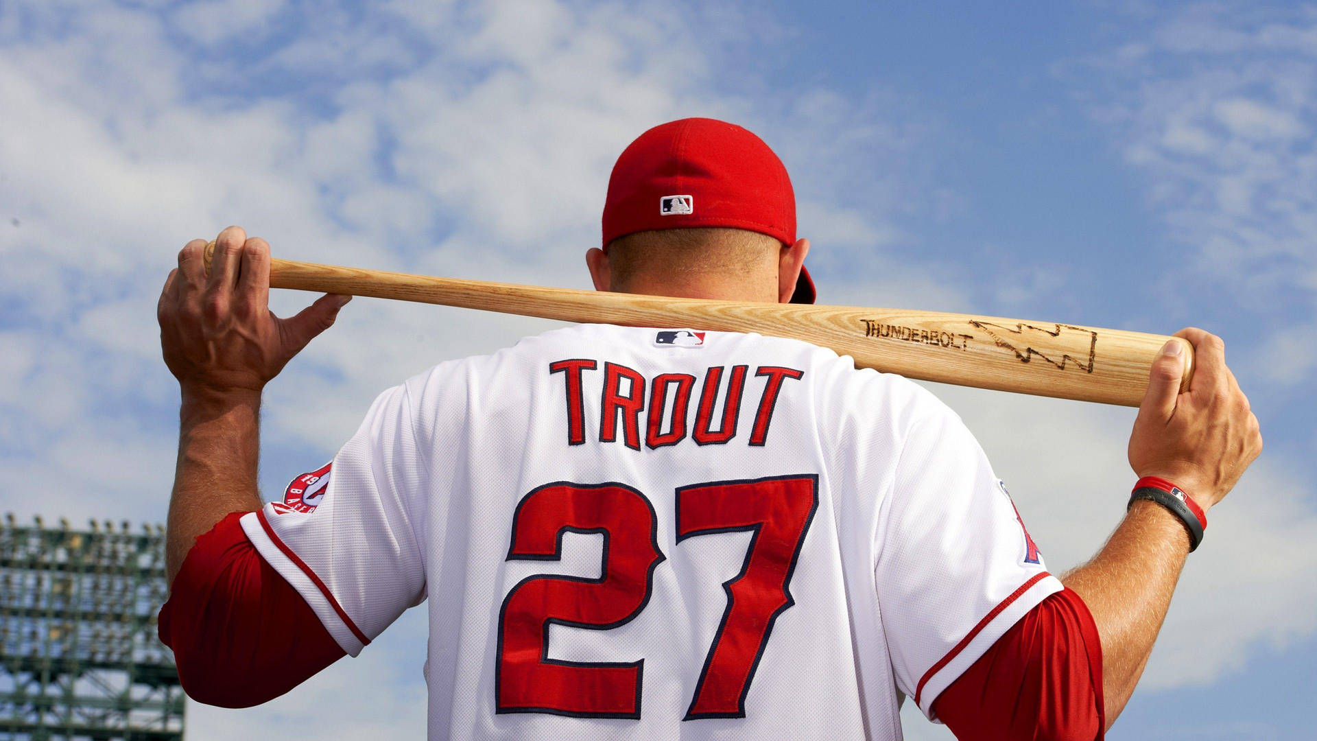 棒球選手Mike Trout戴紅色帽子，穿白色球衣，在戶外將球棒扛在肩上。 — MLB 壁紙