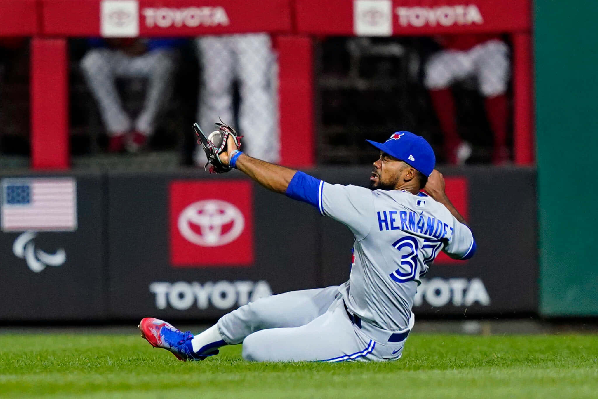 棒球選手在夜間草地上飛撲接球。 — MLB 壁紙