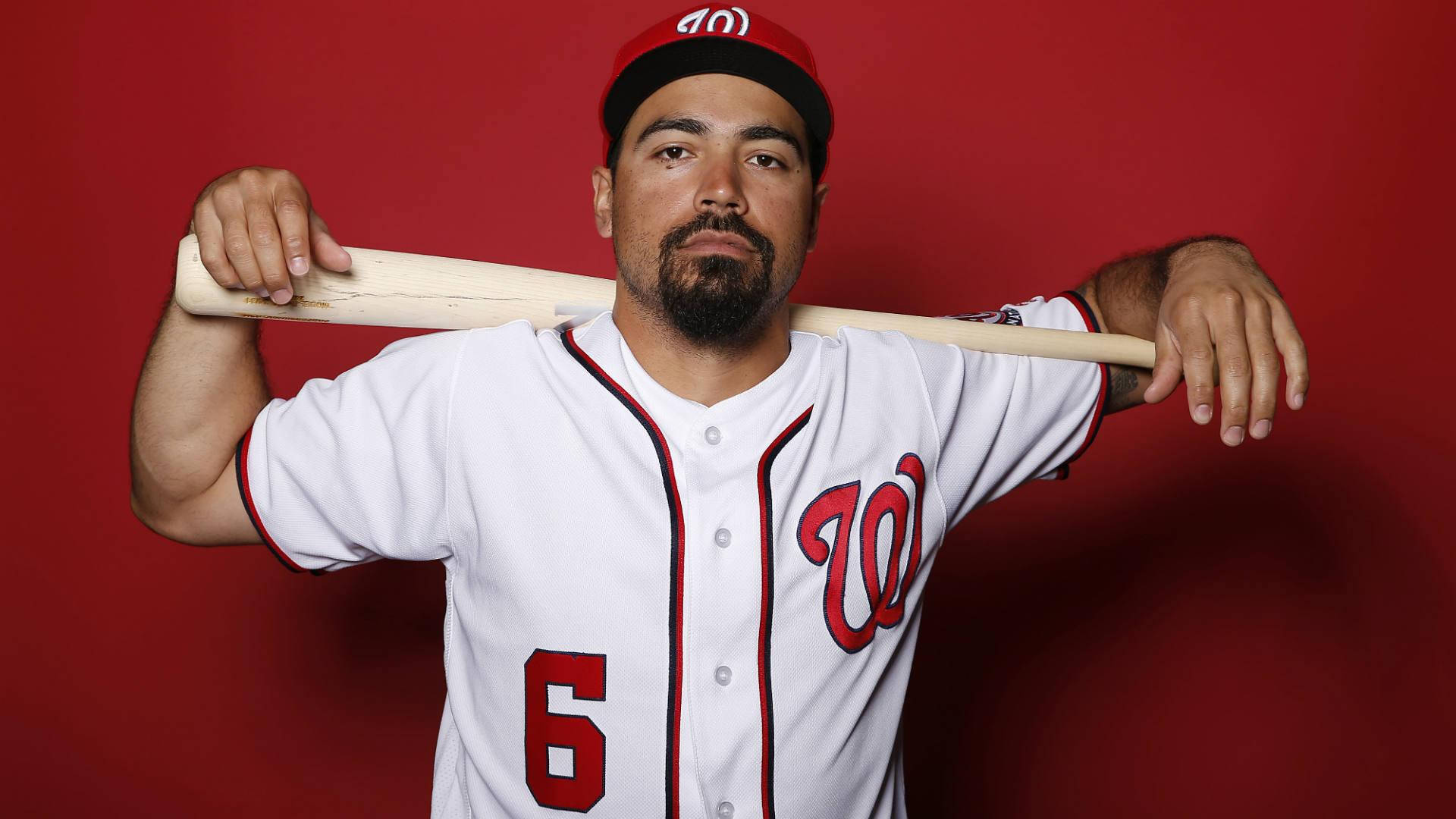 身穿制服的棒球運動員在紅色背景前持球棒。 — MLB 壁紙