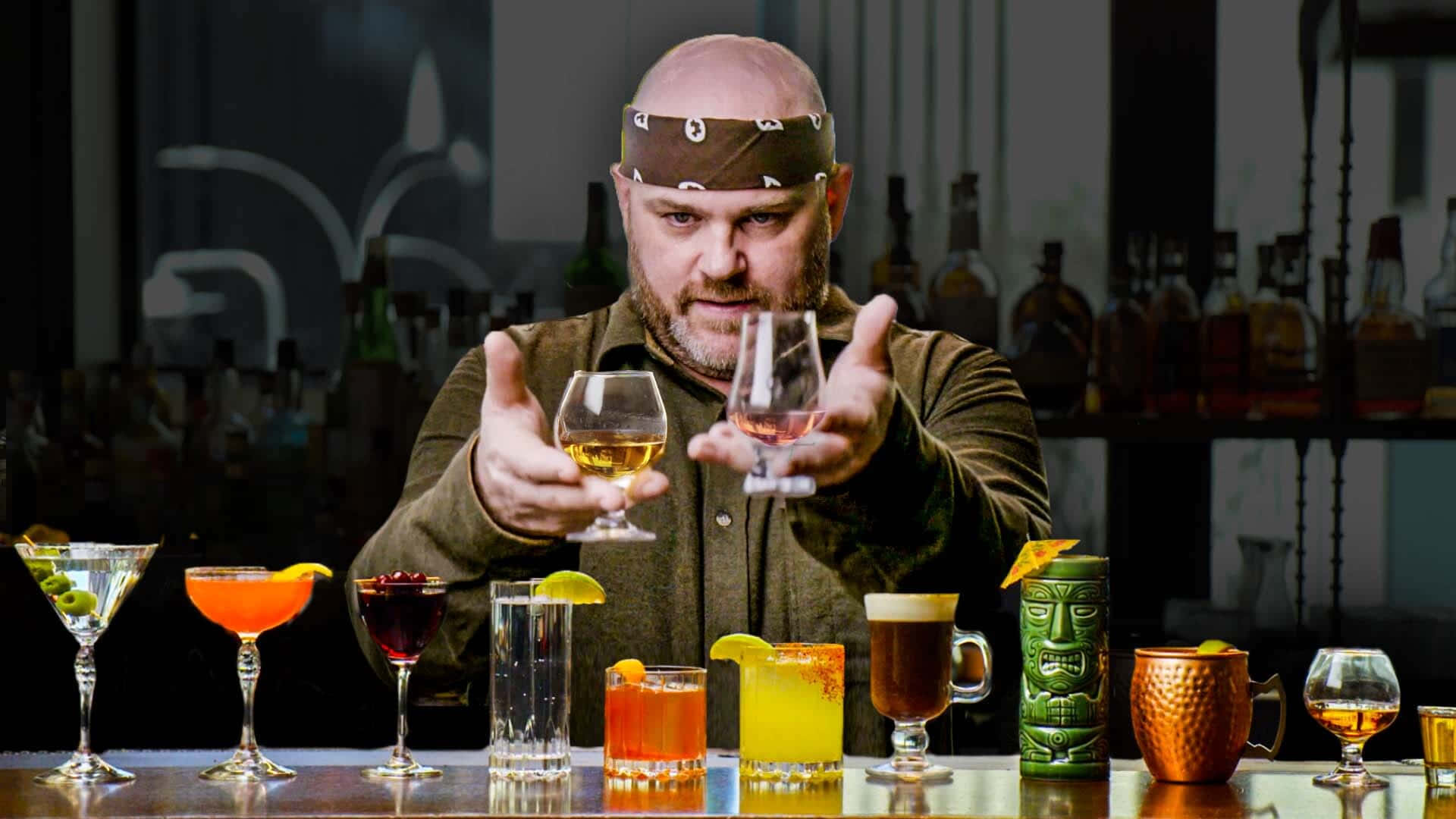  壁紙 — 一位戴著頭巾的酒保在色彩繽紛的飲品環繞下，向鏡頭展示兩杯雞尾酒。