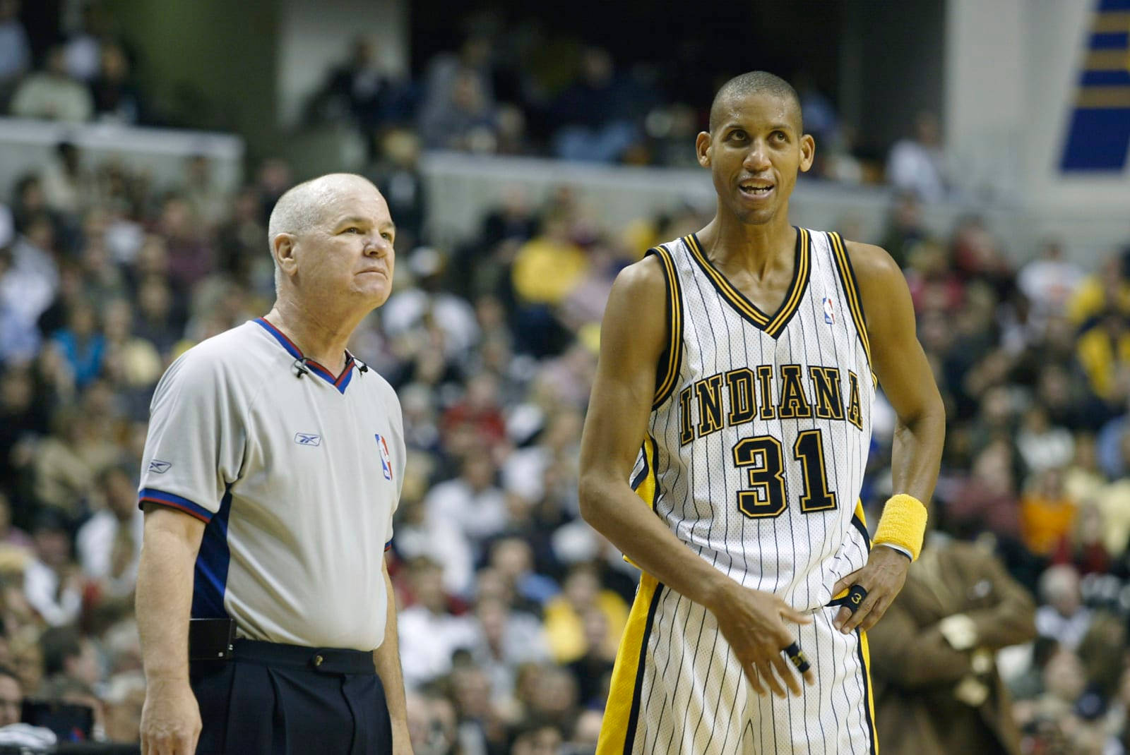 籃球運動員和裁判在比賽中的球場上，後面有群眾。 — NBA 壁紙